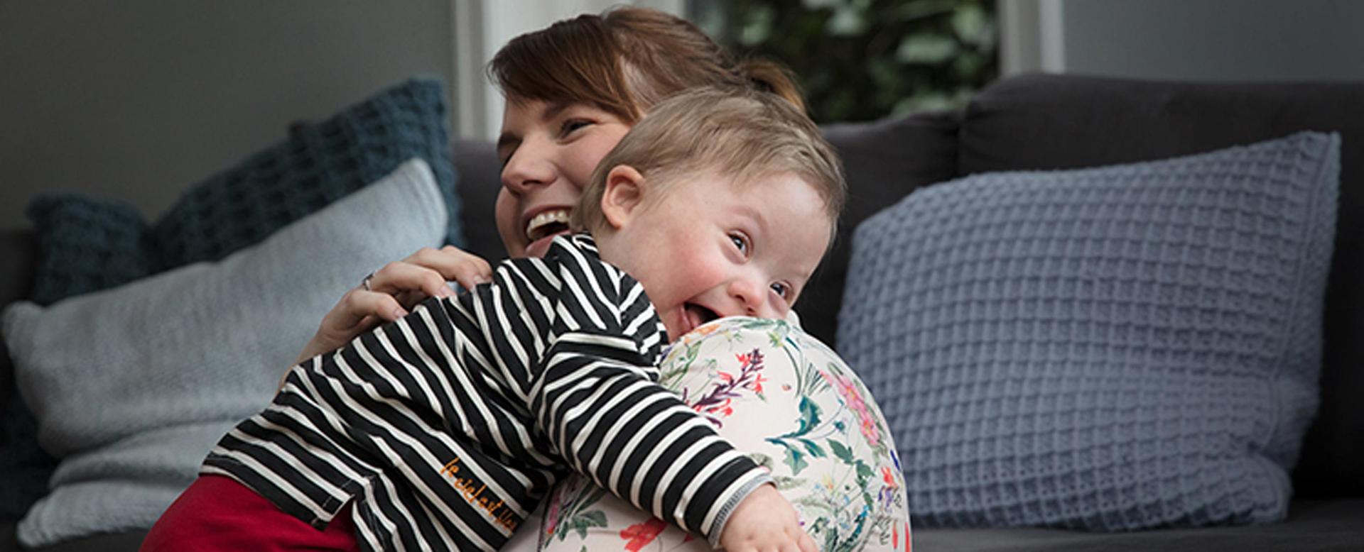 Mother Hugging a Smiling Baby on a Sofa