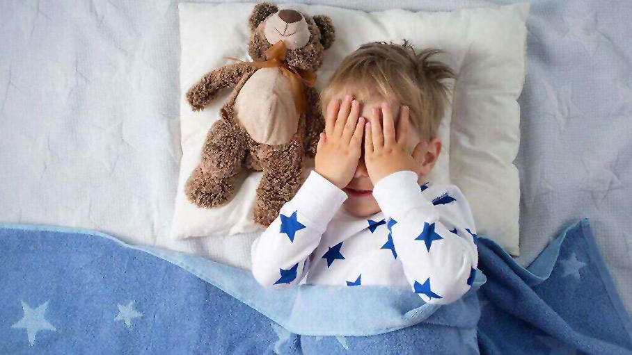 little boy in bed with a teddy bear