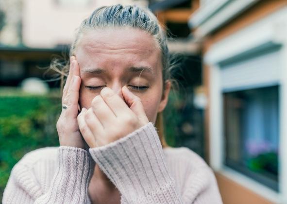 Femme se pinçant le nez et mettant la main sur sa tempe