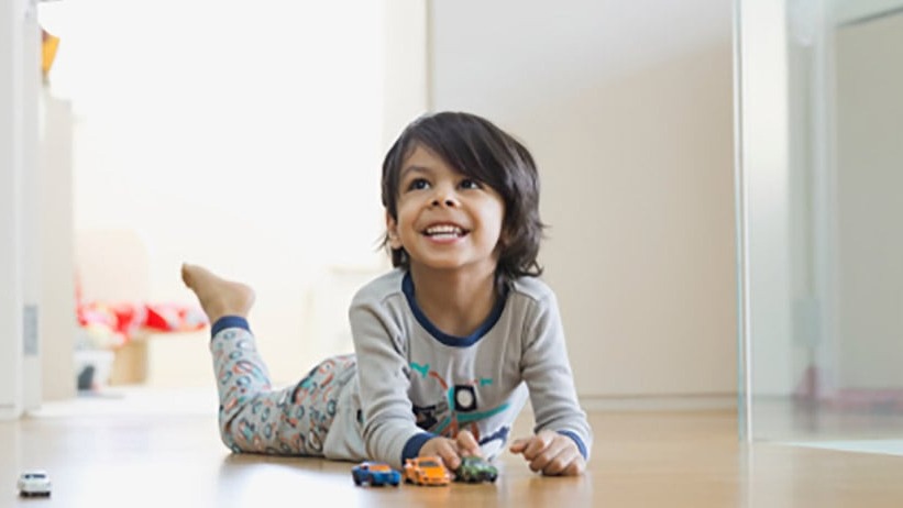 Little boy playing with toy cars on the floor at home