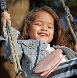 Happy toddler smiling while enjoying the swing outdoors