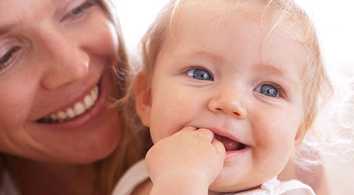 Mom smiling and carrying her teething baby