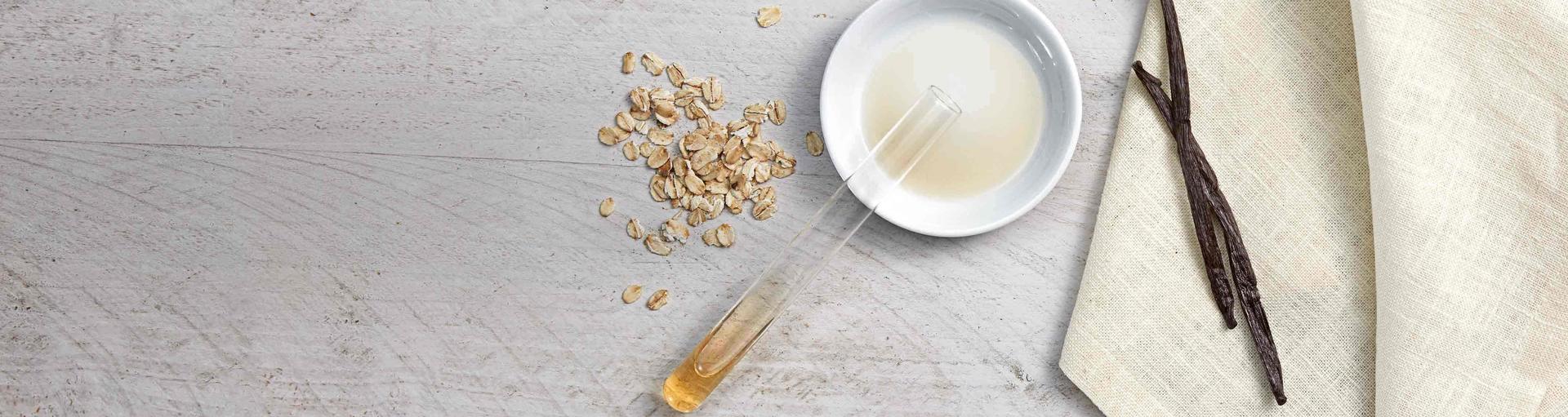 Flat lay of oats, oat extracted formula in a tube, and vanilla beans