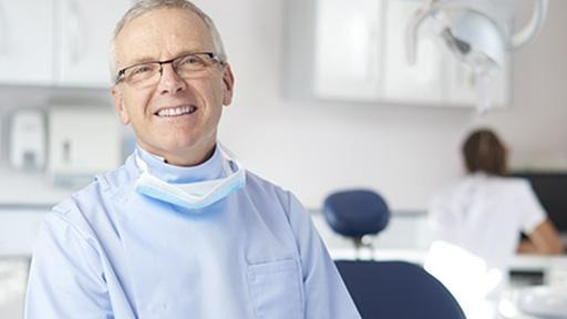 dentiste qui sourit dans son cabinet