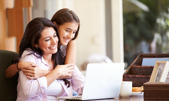 A woman and her teenage daughter shopping online on a laptop