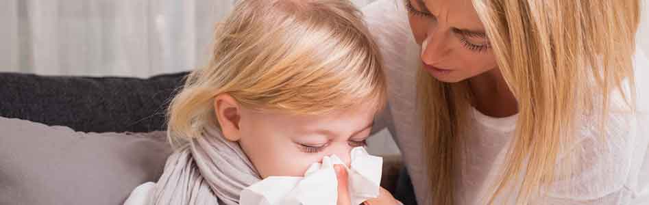 Mother helping her daughter blow her nose