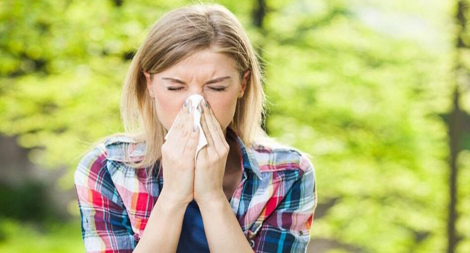 Woman blowing nose outdoors in a forest