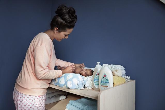 Baby next to Johnson’s® newborn skin care products