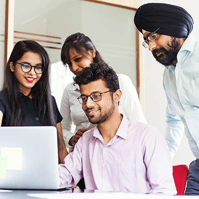 Four employees gathered in front of a laptop in the office