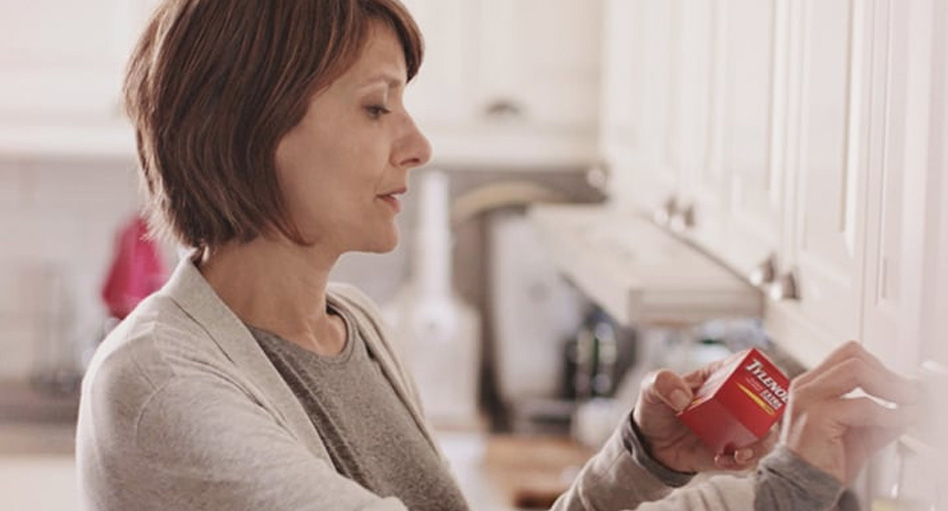 Femme qui lit l'étiquette d'une boîte de Tylenol