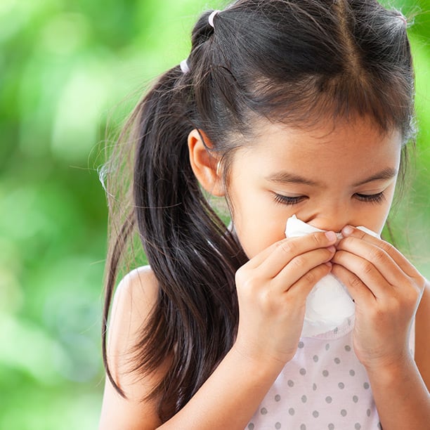 Little girl browing her nose into paper napkin