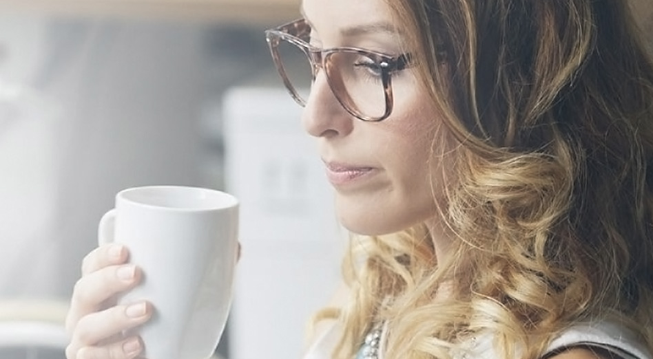 Woman holding a cup and reading on a tablet