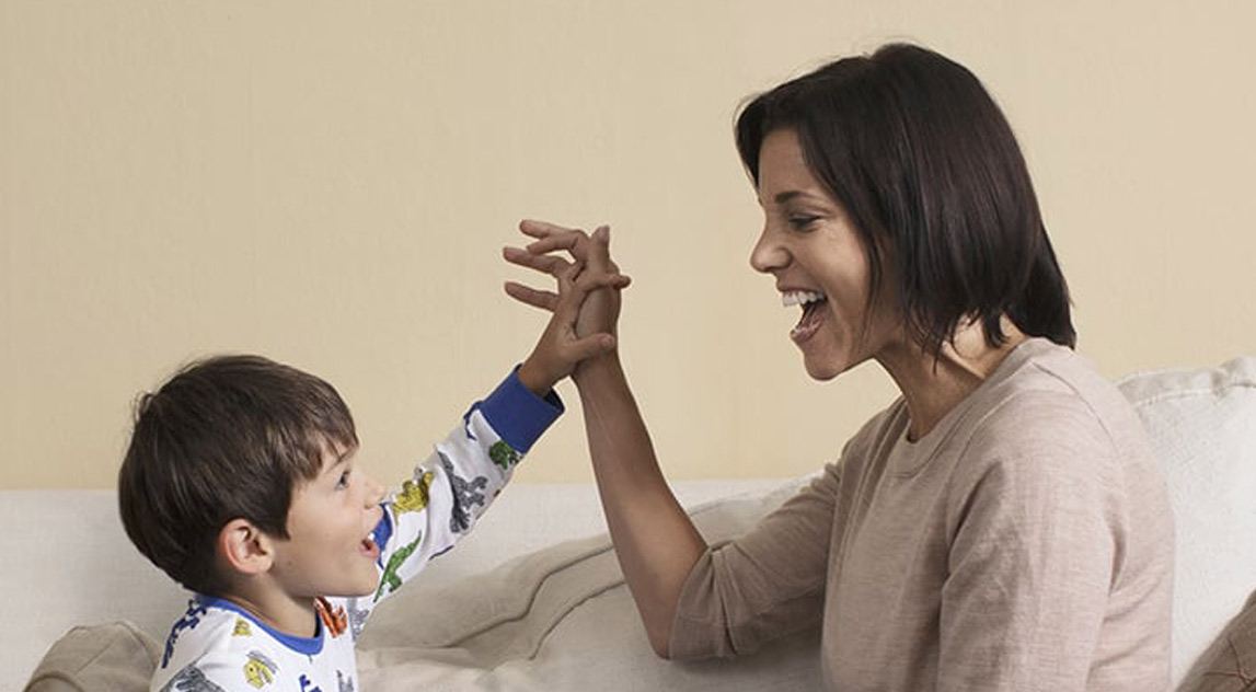 Woman playing with her son on a couch