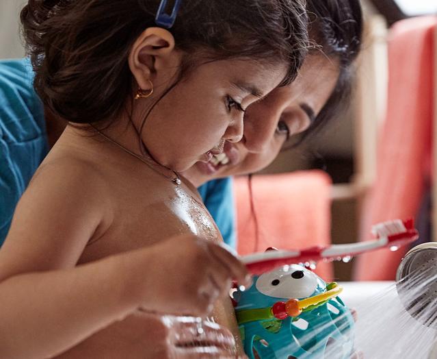 Parent helping Toddler to brush teeth in the sink