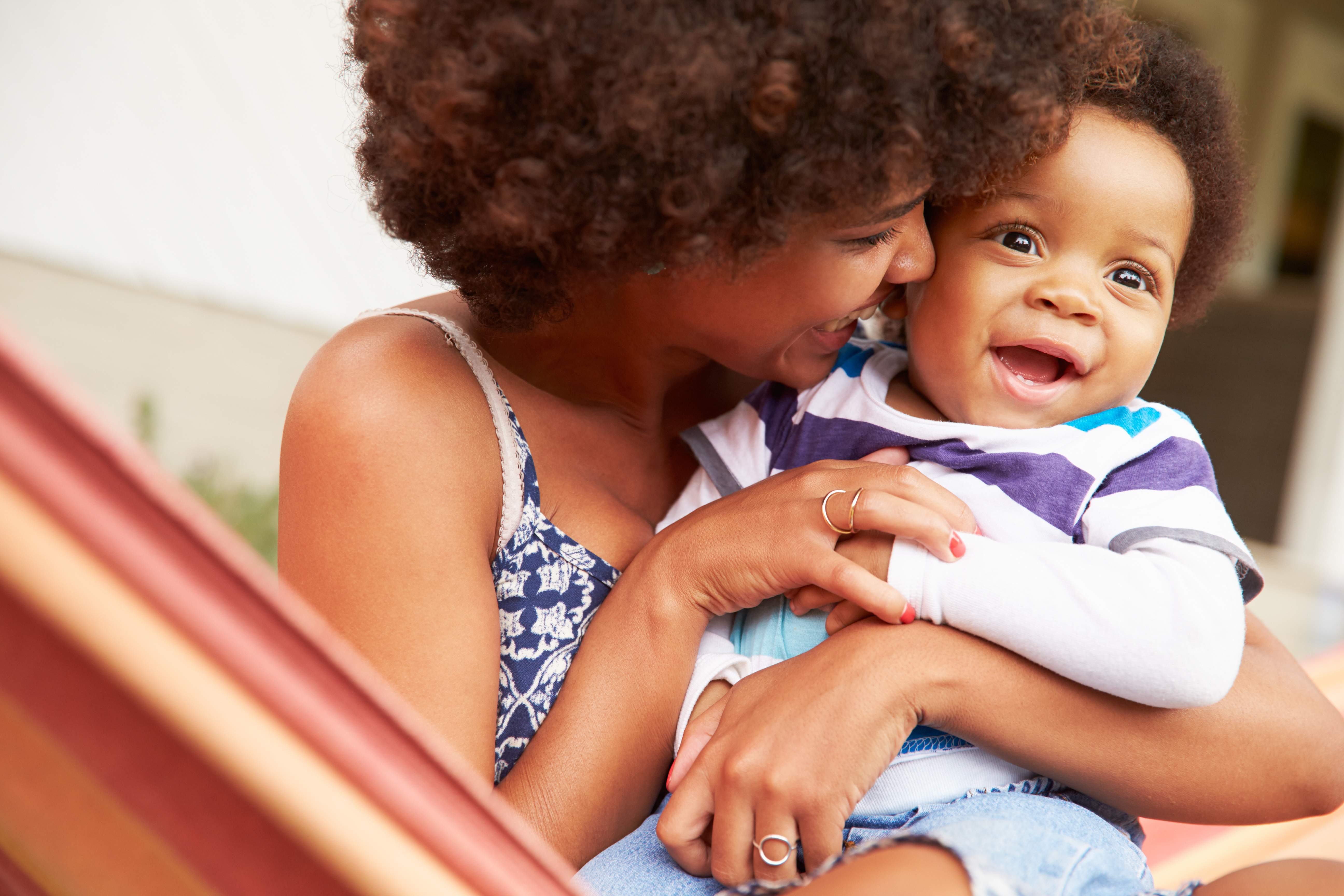 Femme qui tient son jeune enfant dans ses bras tout en lui souriant.