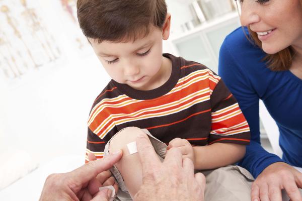 Personne qui couvre une plaie mineure au genou d'un enfant avec un pansement Band-Aid®