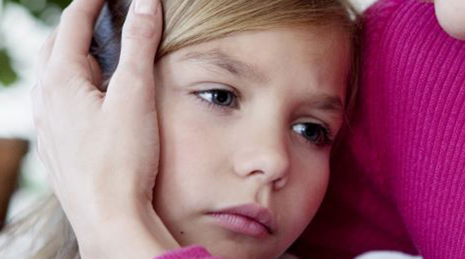 Girl having her ear covered by her mother