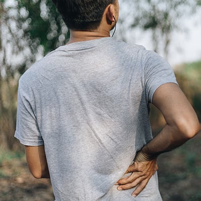 Man walking outside and holding his lower back