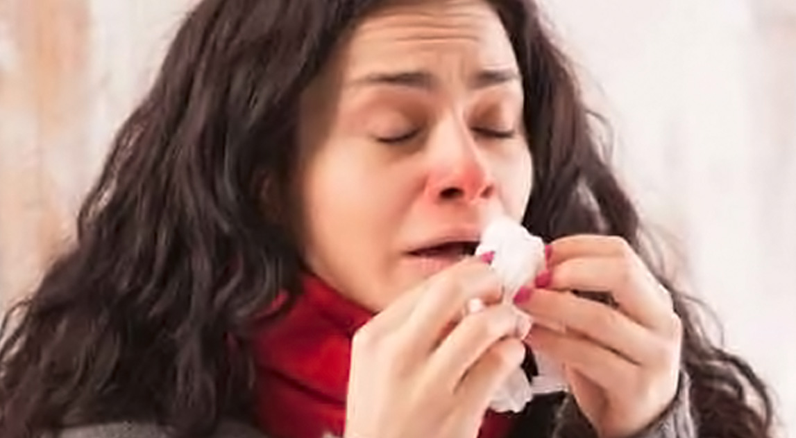 Woman trying to hold back a sneeze with a tissue in her hand