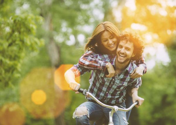 A couple smiling and riding a bike together