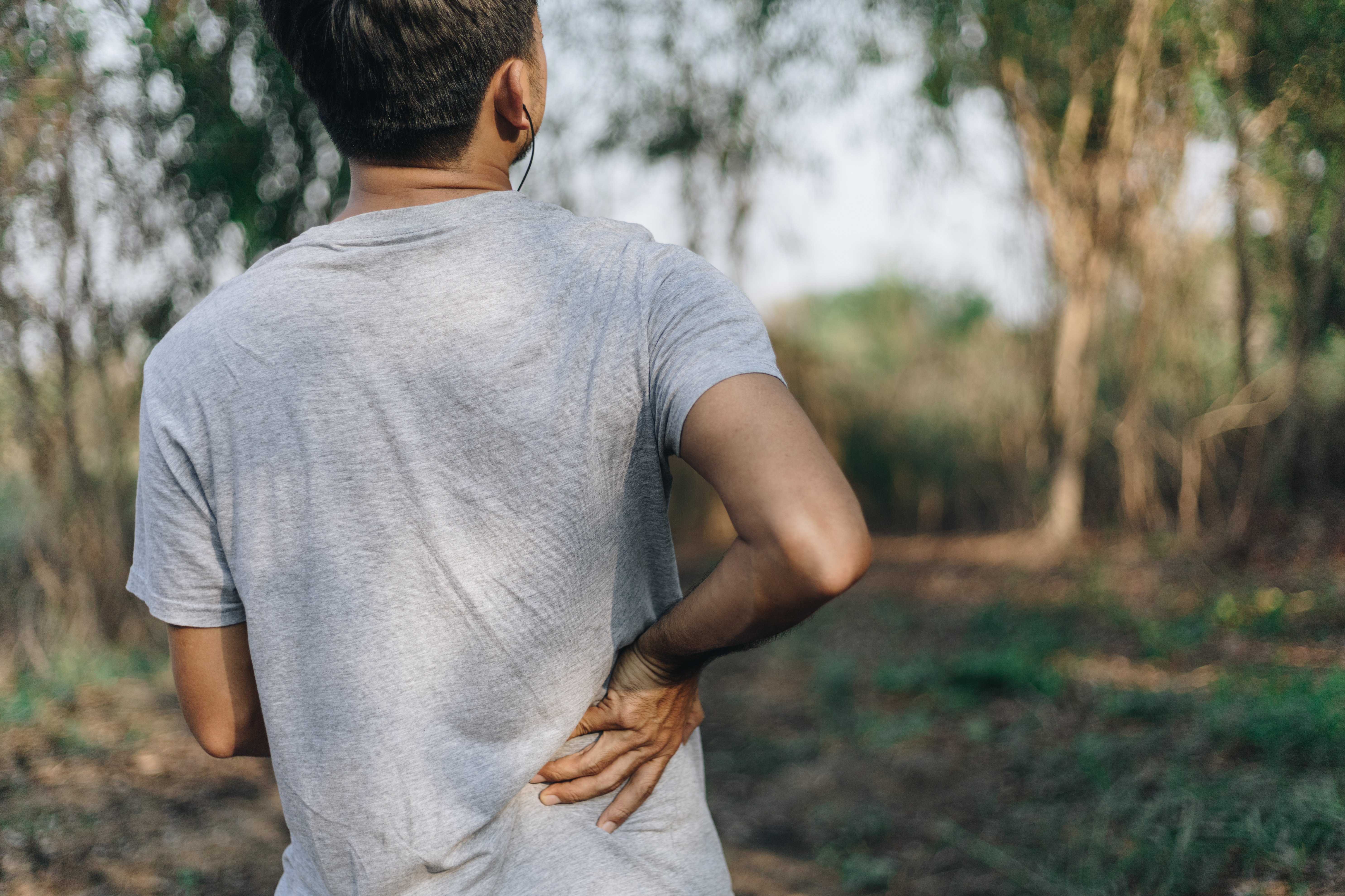 Man experiencing lower back pain and holding his back in discomfort.