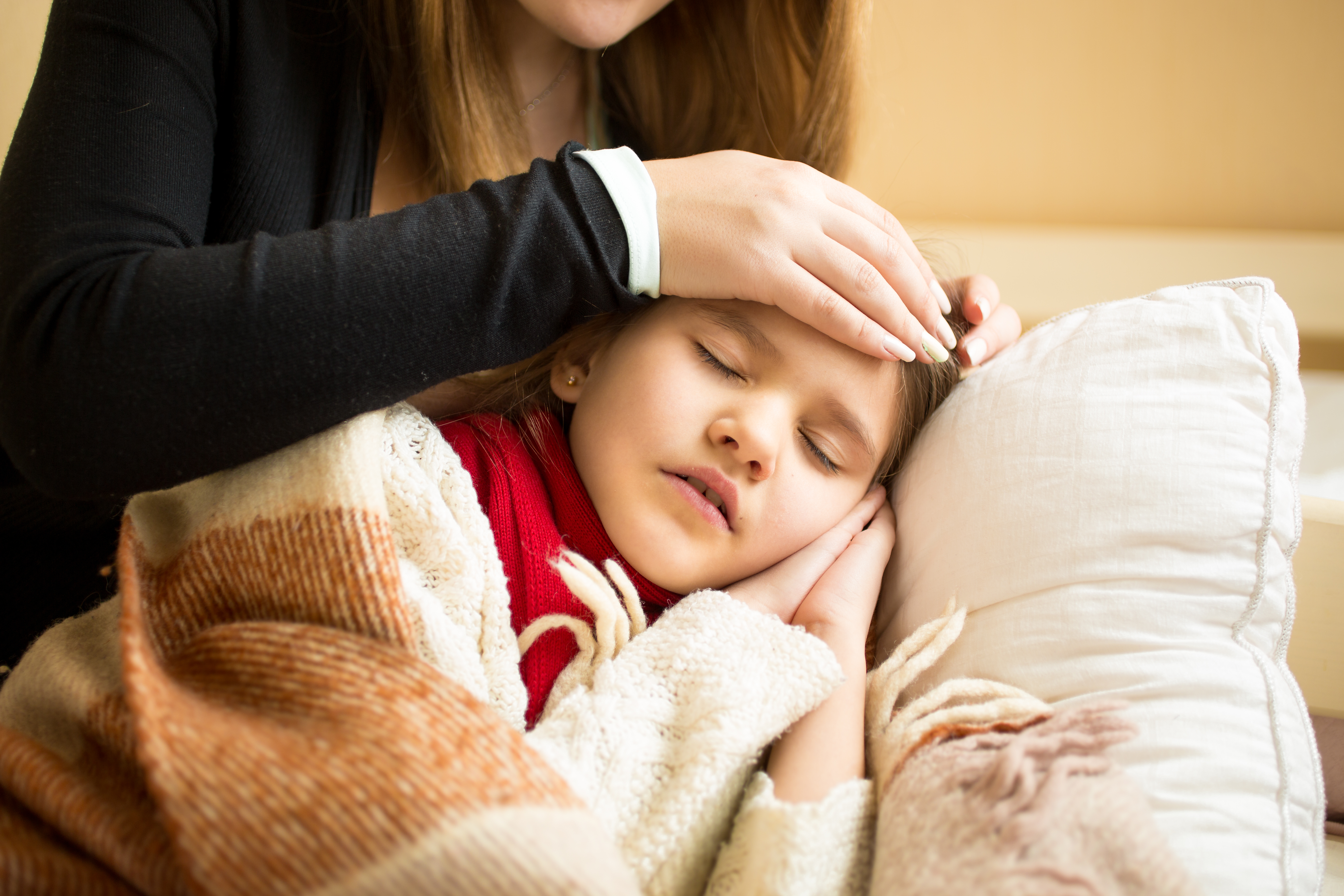 A little girl sleeping while her mum checks her temperature with hand