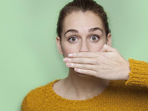 woman afraid of bad breath covering up mouth with her hand