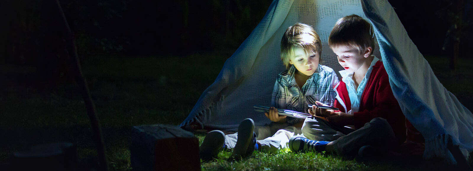 two children sitting inside a tipi