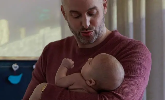 Un papa berçant son bébé pour l’endormir