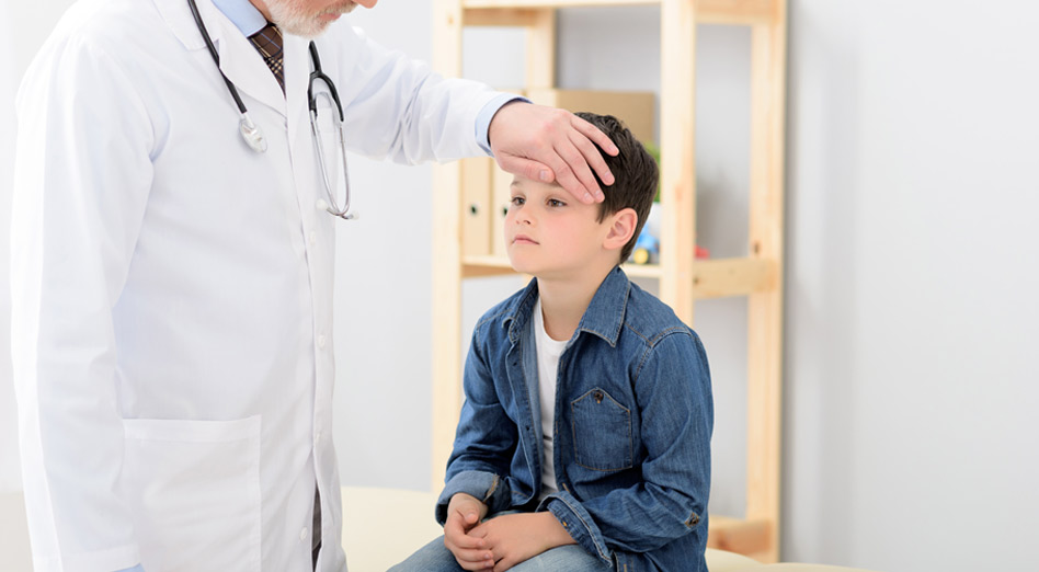 Doctor checking temperature of a little boy with his hand