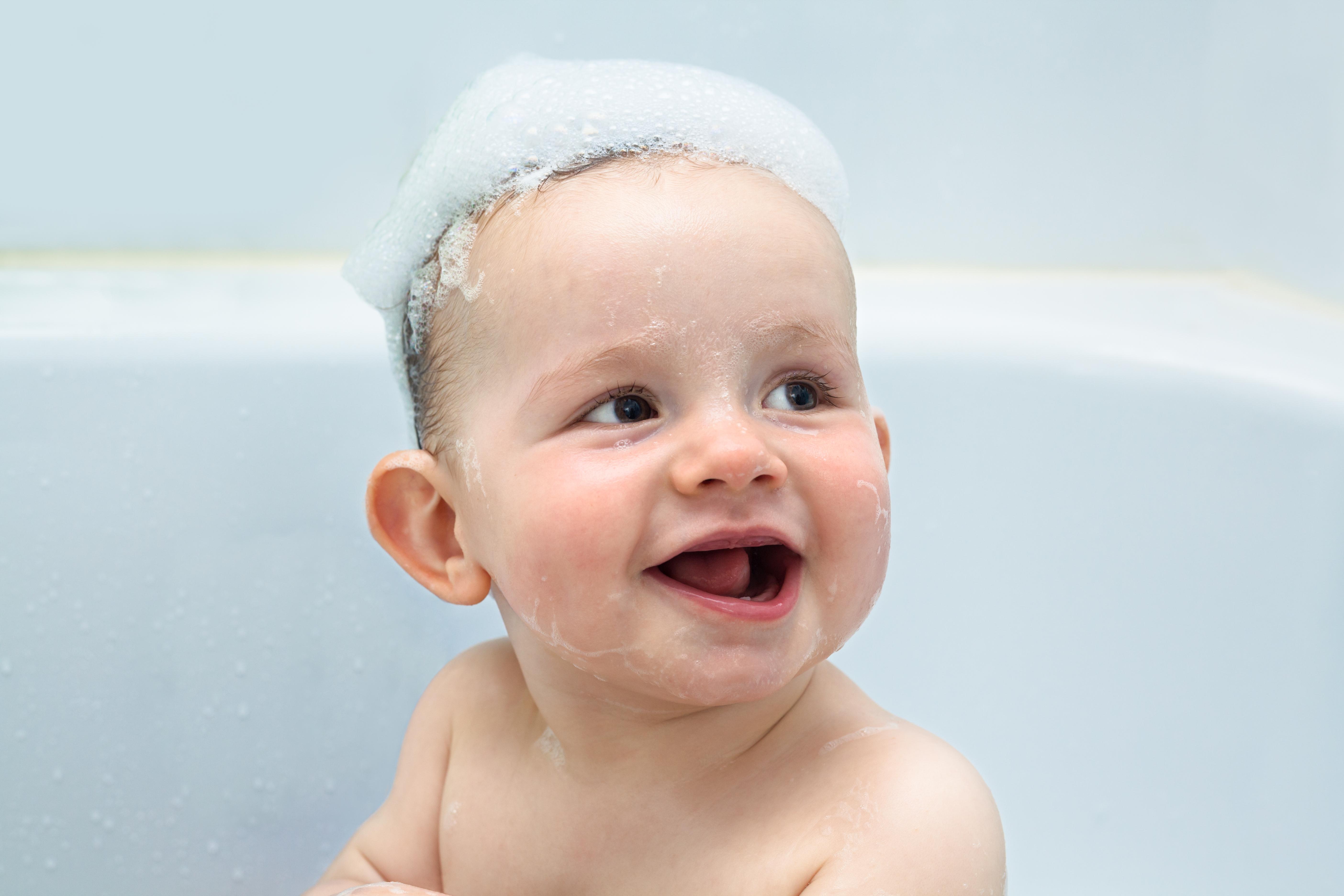 A banner displaying a cute baby taking a bubble bath and smiling.