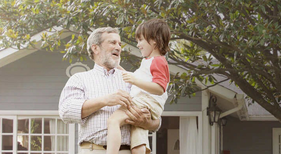 Grandfather carrying his  grandson in the garden