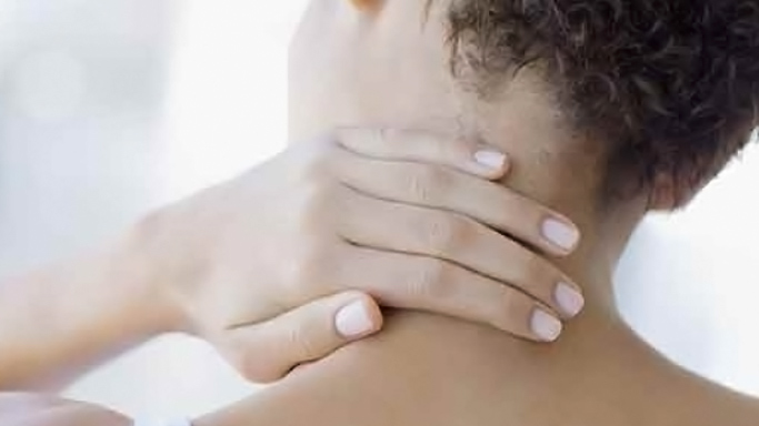 Woman who is experiencing muscle strain holding the back of her neck