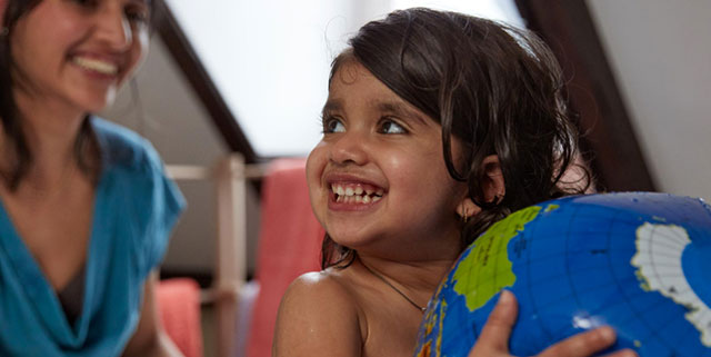 girl with globe smiling at teacher