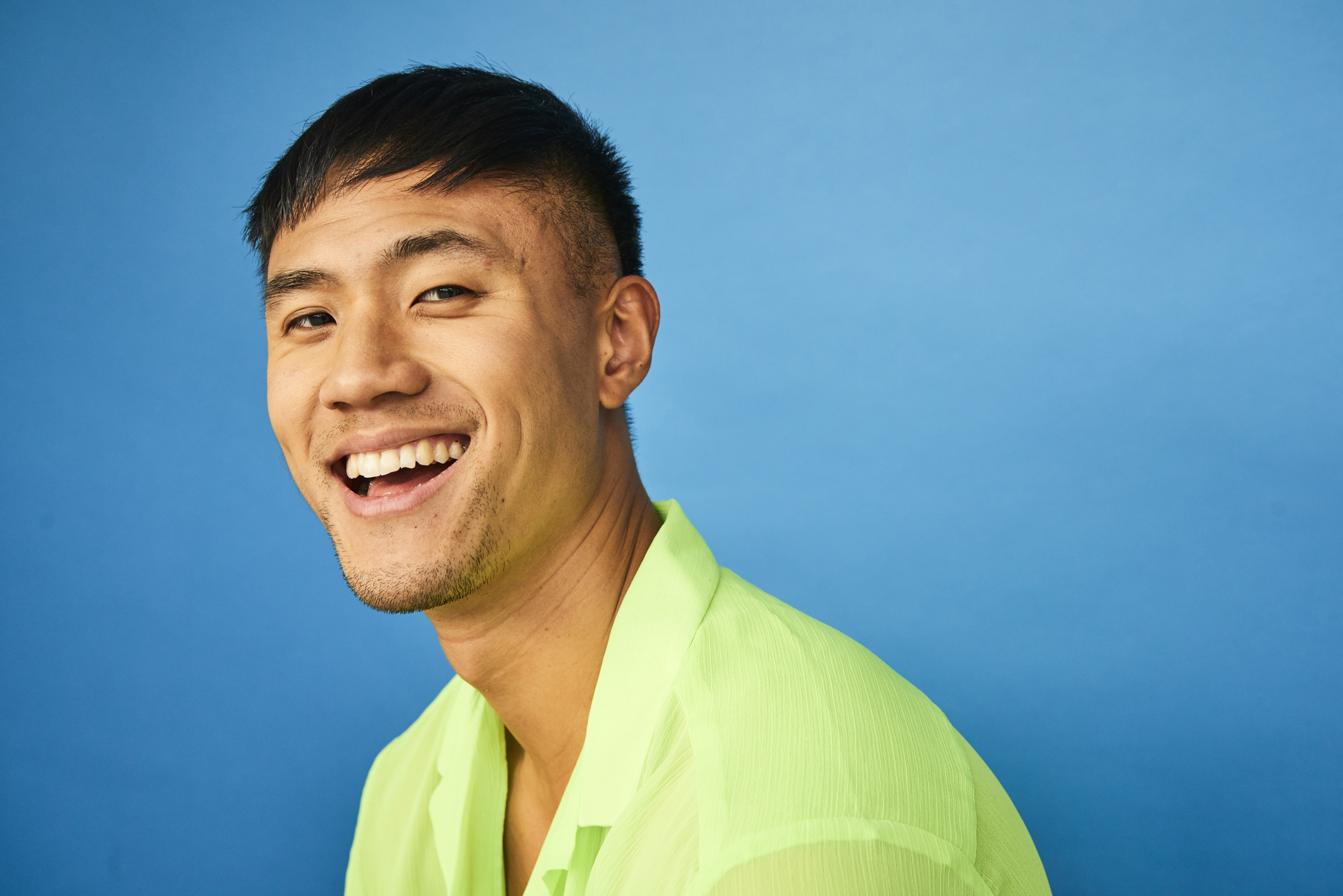 Jeune homme souriant portant une chemise verte