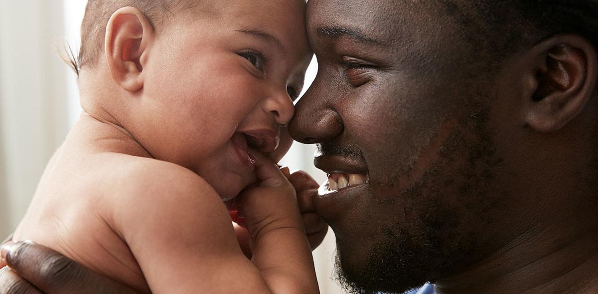 Father Carrying a Baby and Smiling Together