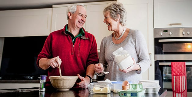 Elderly couple enjoying and preparing a meal together