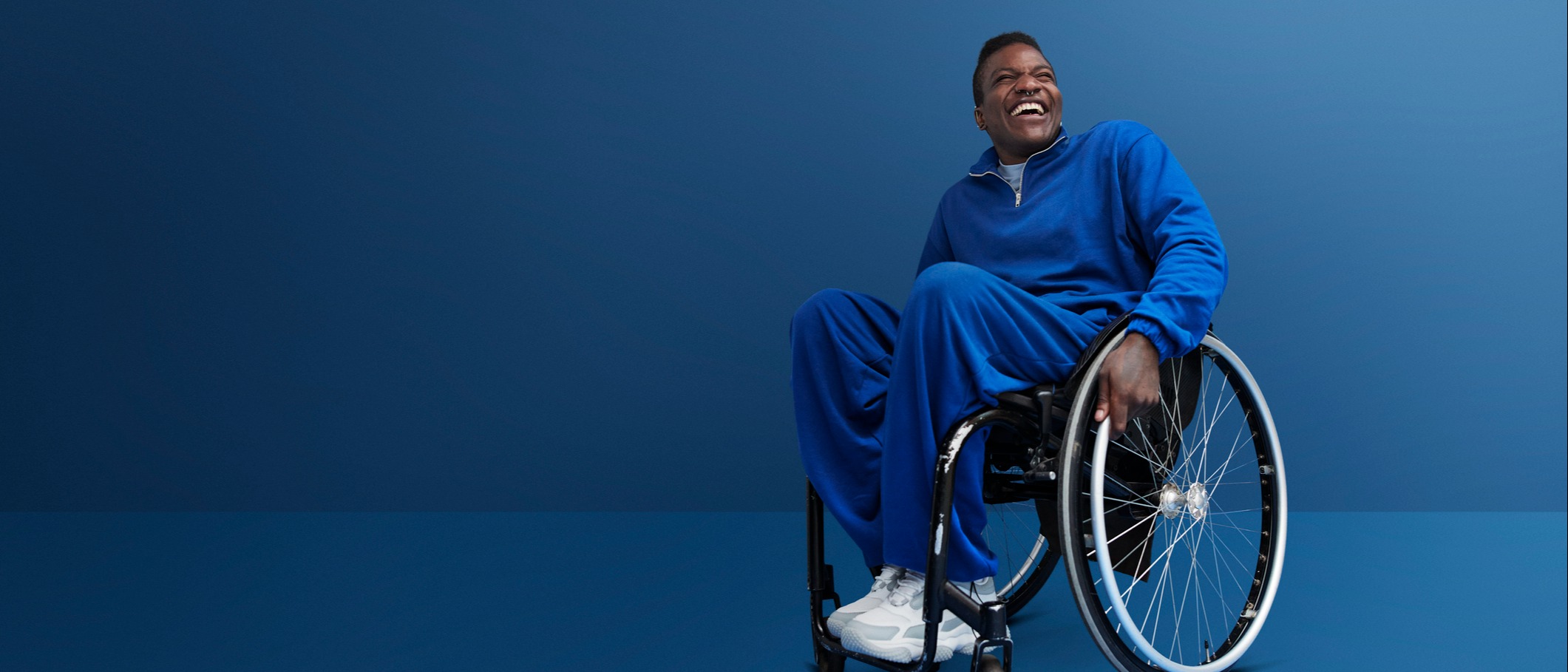 homme souriant habillé de bleu assis sur un fauteuil roulant | LISTERINE