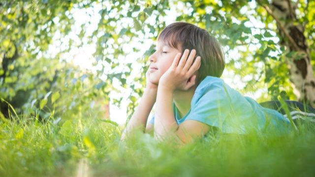 Un garçon allongé sur la pelouse avec la tête reposant entre ses mains