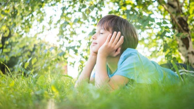 A boy lying on the grass and resting head in hands