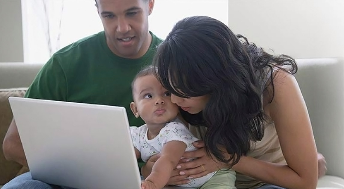 Parents using a laptop with their toddler child 