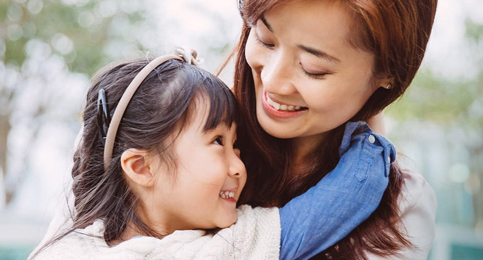 A little girl and her mother smiling at each other.