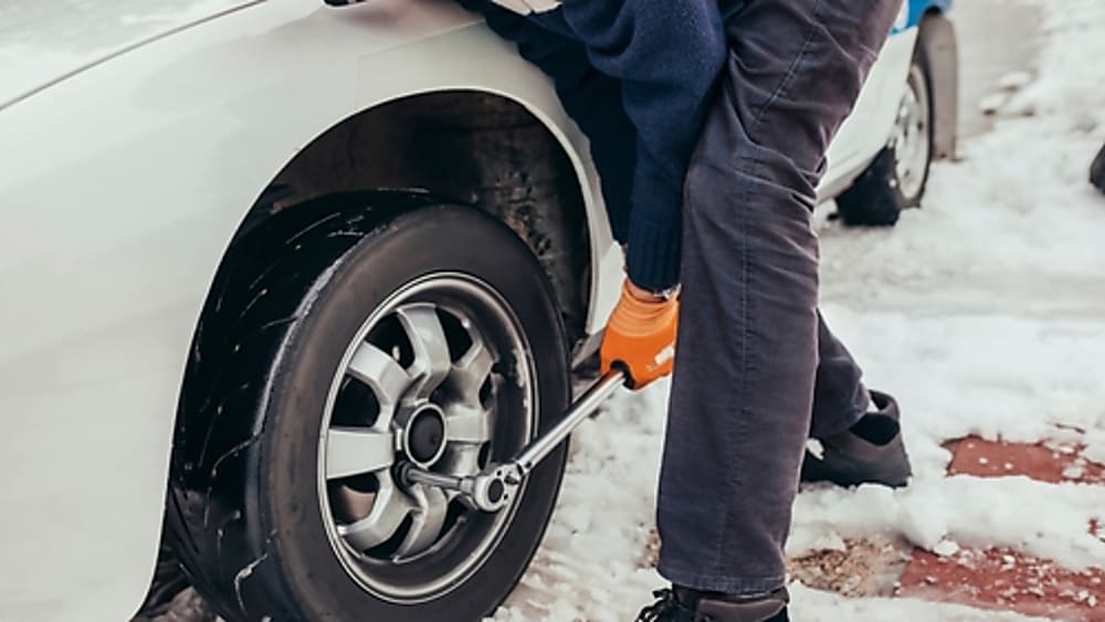 Professional roadside assistance helping with a tire in snow