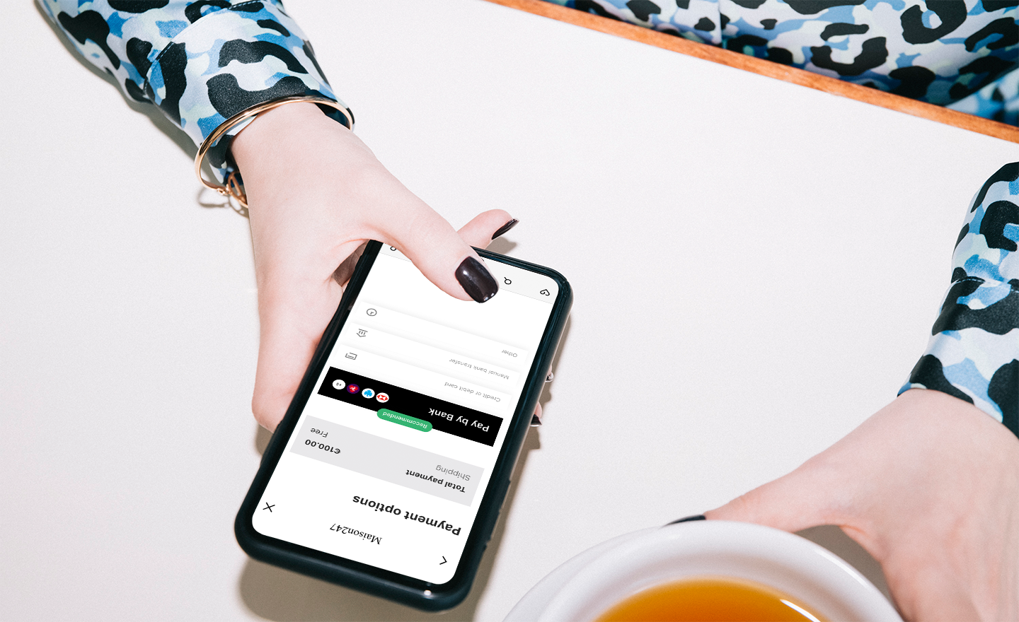 A person viewing a mobile phone from above, which displays a payment transaction using Pay by Bank.