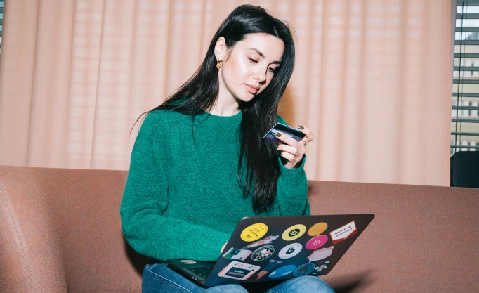 Mujer de pelo oscuro pagando con tarjeta de crédito en un ordenador portátil