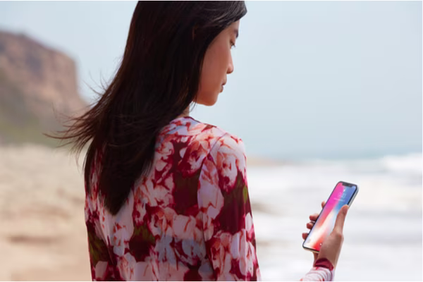 Woman on beach looking at iPhone X screen
