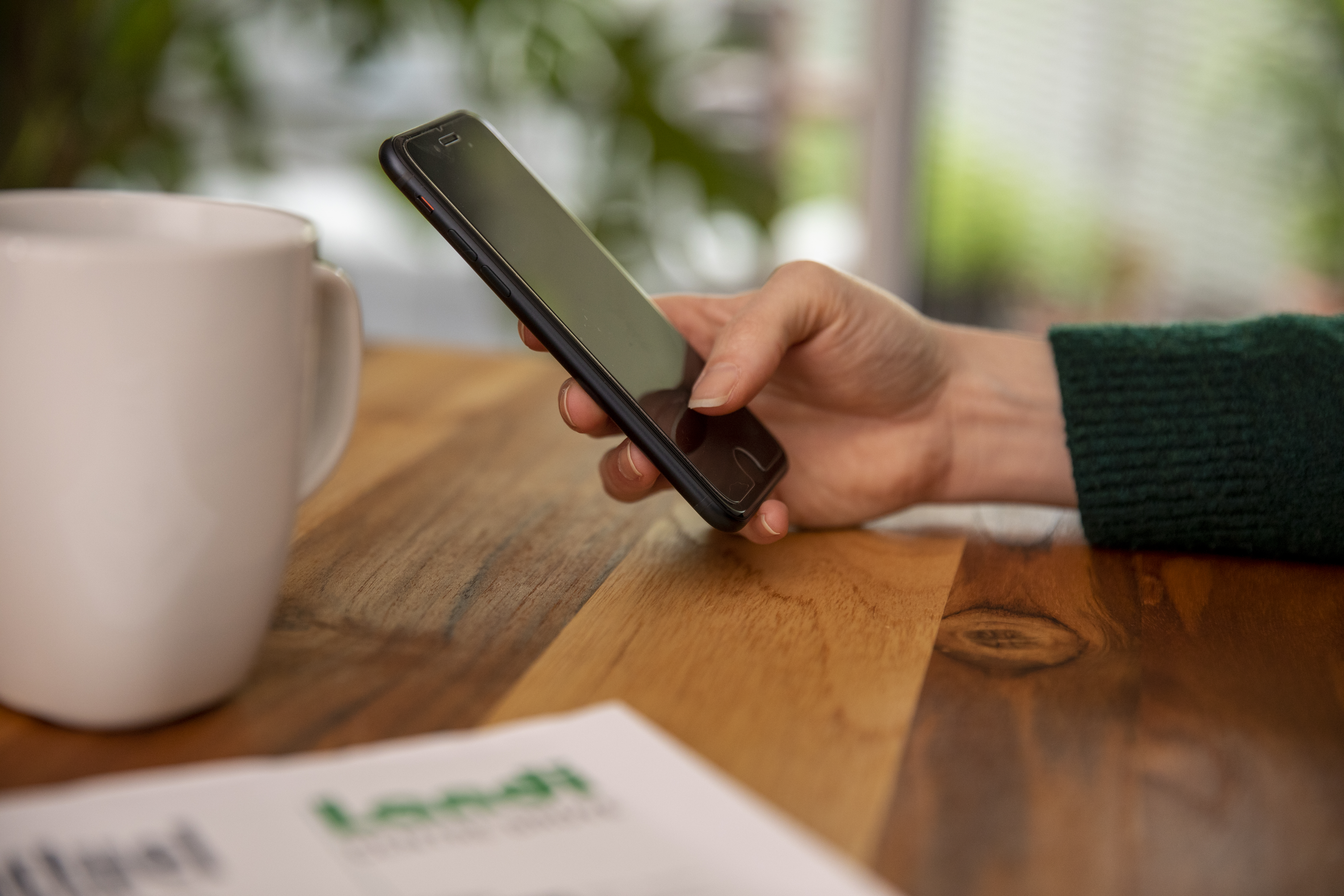 Hand mit Handy, Kaffeetasse und AGROaktuell angeschnitten auf Tisch