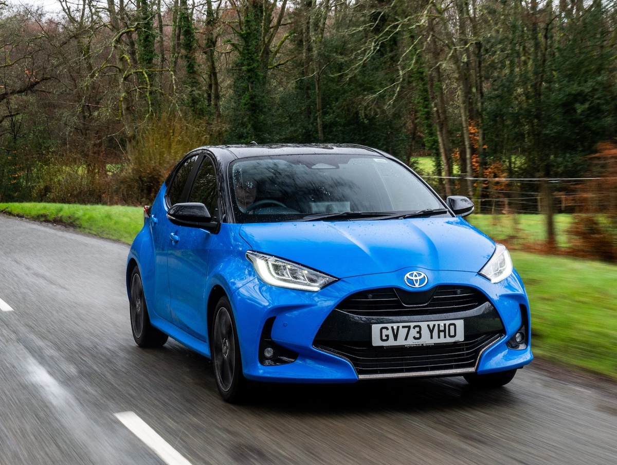 A front view of a blue 2024 Toyota Yaris driving on a road.