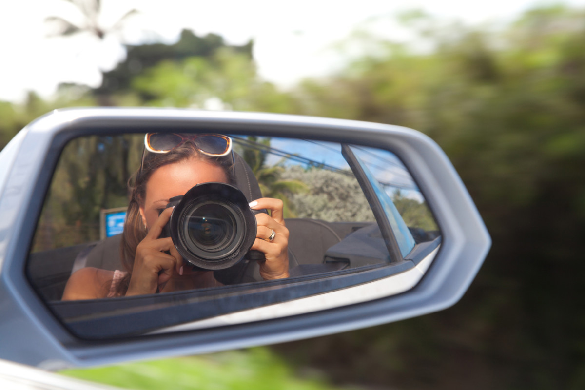 Woman taking photo of car mirror