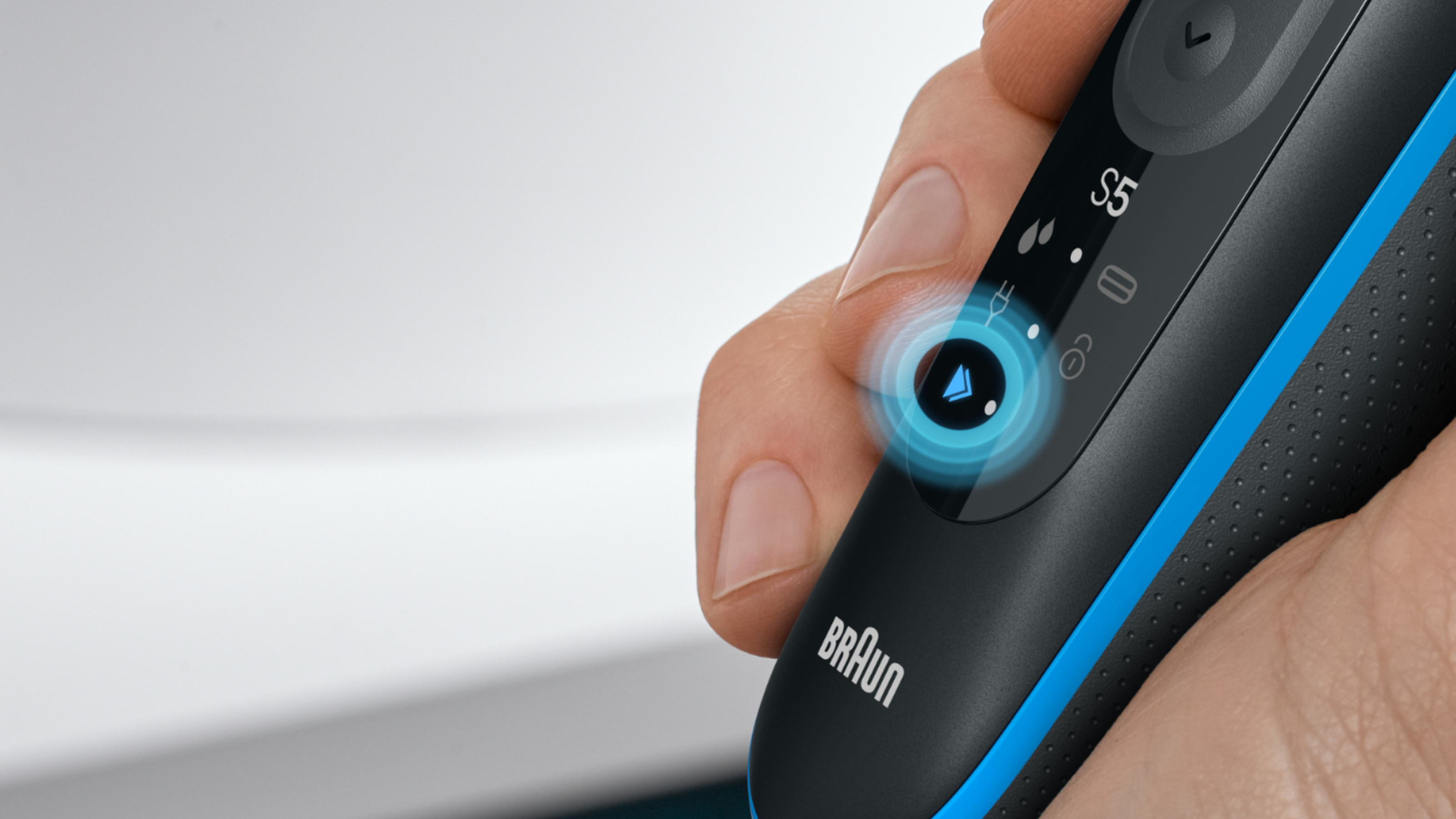 Hand holding shaver device, two triangles symbolizing the "Turbo mode" are shining blue, framed by a blue circle